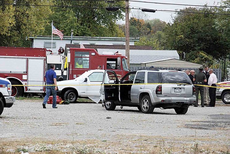 Wood County Prosecutor Jason Wharton walks toward the truck where Parkersburg Police say a murder suspect shot himself in the head Wednesday afternoon behind O'Reilly Auto Parts on Division Street. A woman in the vehicle with him took her own life as well. (Photo by Evan Bevins)